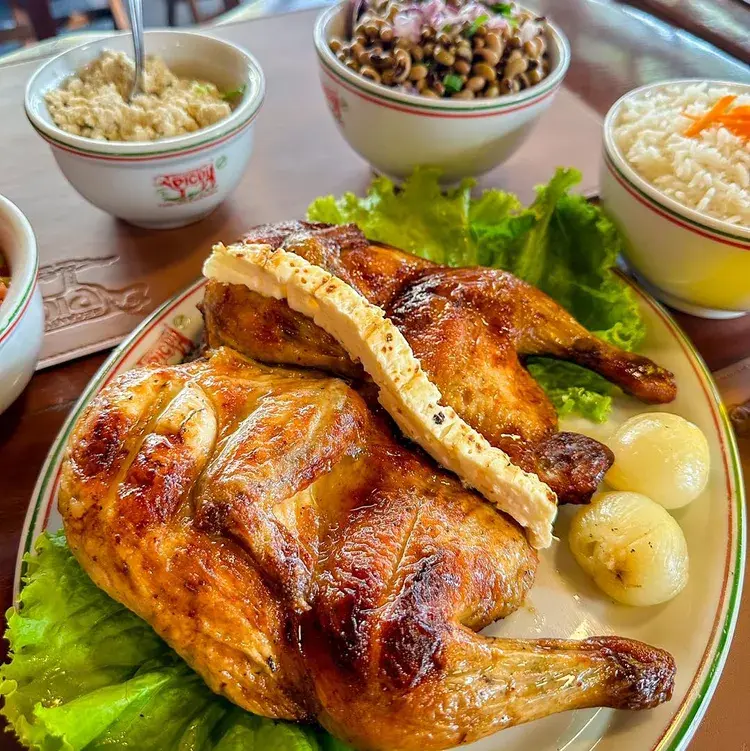 Cachaça sendo servida em um copo com gelo e limão, com duas garrafas de cachaça ao fundo.