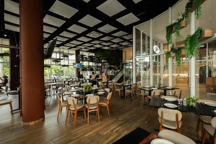 Interior do restaurante Johns - Grill, Wine and Salad, com mesas preparadas para o almoço.