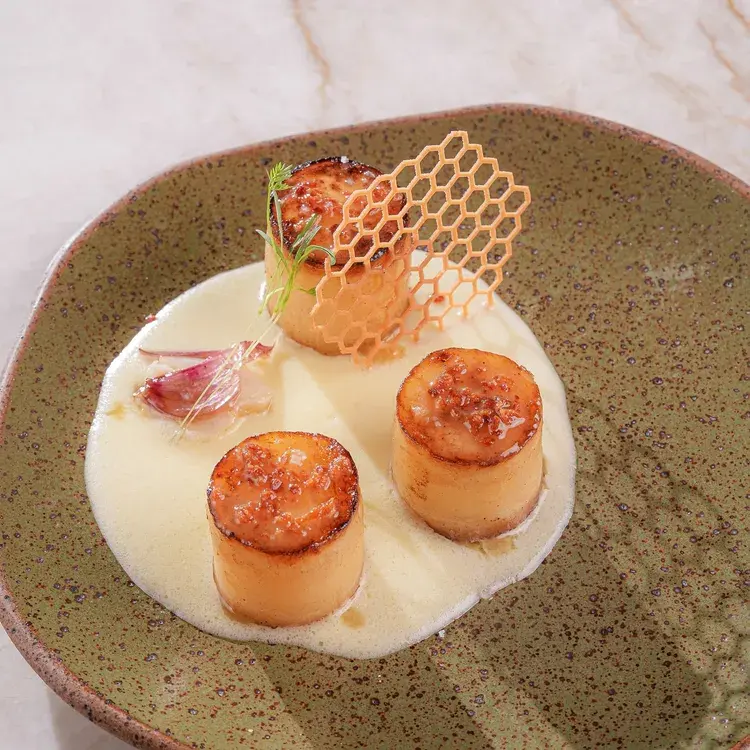 Prato do Menu Week 2025 na Tartuferia Savitar, com batata, parmesão e bacon, servido com um molho cremoso.