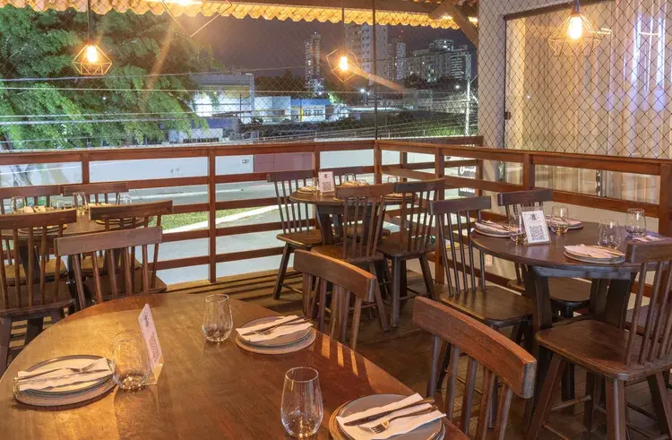 Imagem mostra pessoas reunidas ao redor de uma mesa em ambiente interno com iluminação aconchegante, texto na imagem anuncia 'Confraternização de fim de ano no Caravela' com detalhes sobre ambientes e opções de menu, contato para reservas e logo do Caravela Gastrobar e Bistrô.