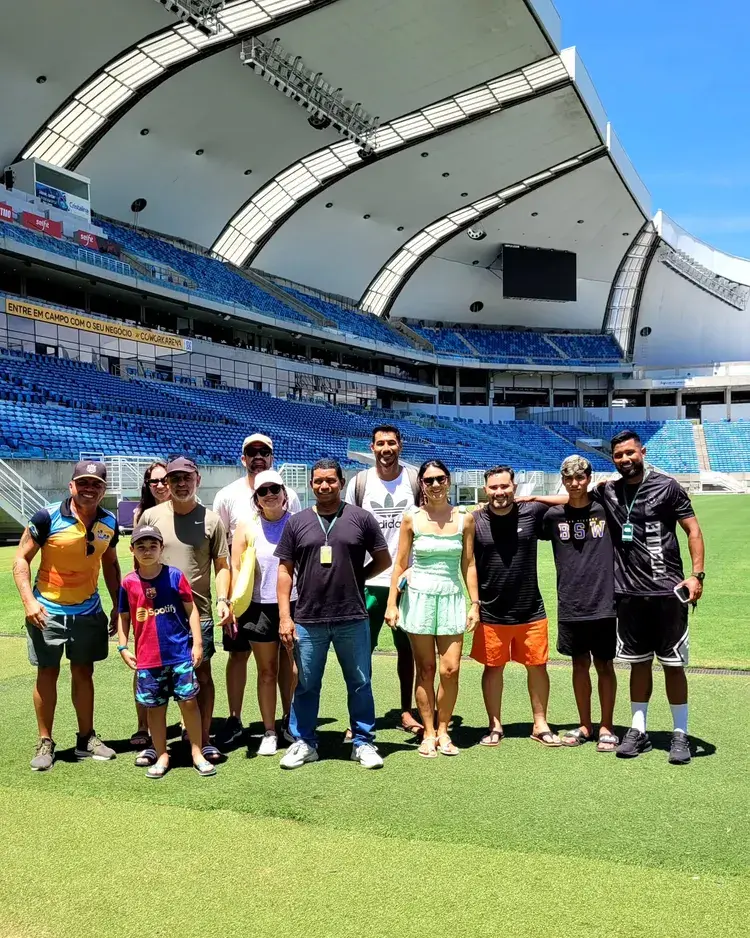 Imagem do grupo de visitantes na Arena das Dunas em campo, e imagem do desafio do gol com bola e alvo, texto 'VOCÊ ENCARA O DESAFIO?' e logo Arena Tour.